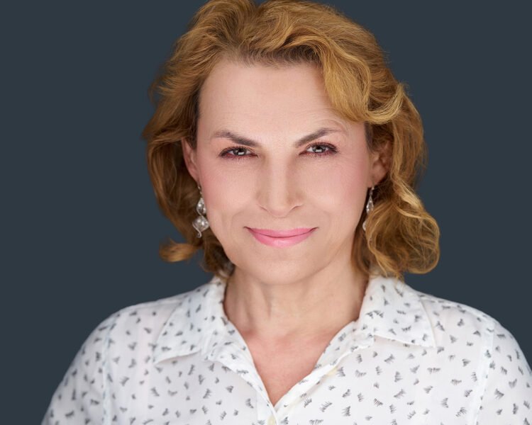 Headshot of Blonde client in her late 60s wearing a white patterned blouse